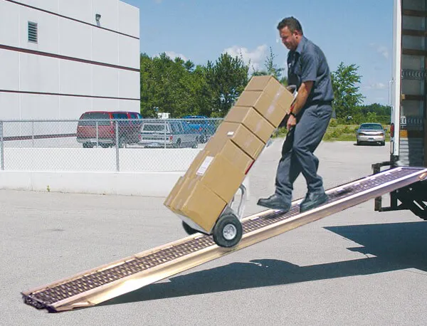 person rolling hand cart with boxes down slide ramp